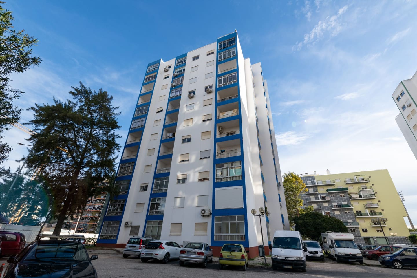 Torre residencial de fachada branca com remates azuis